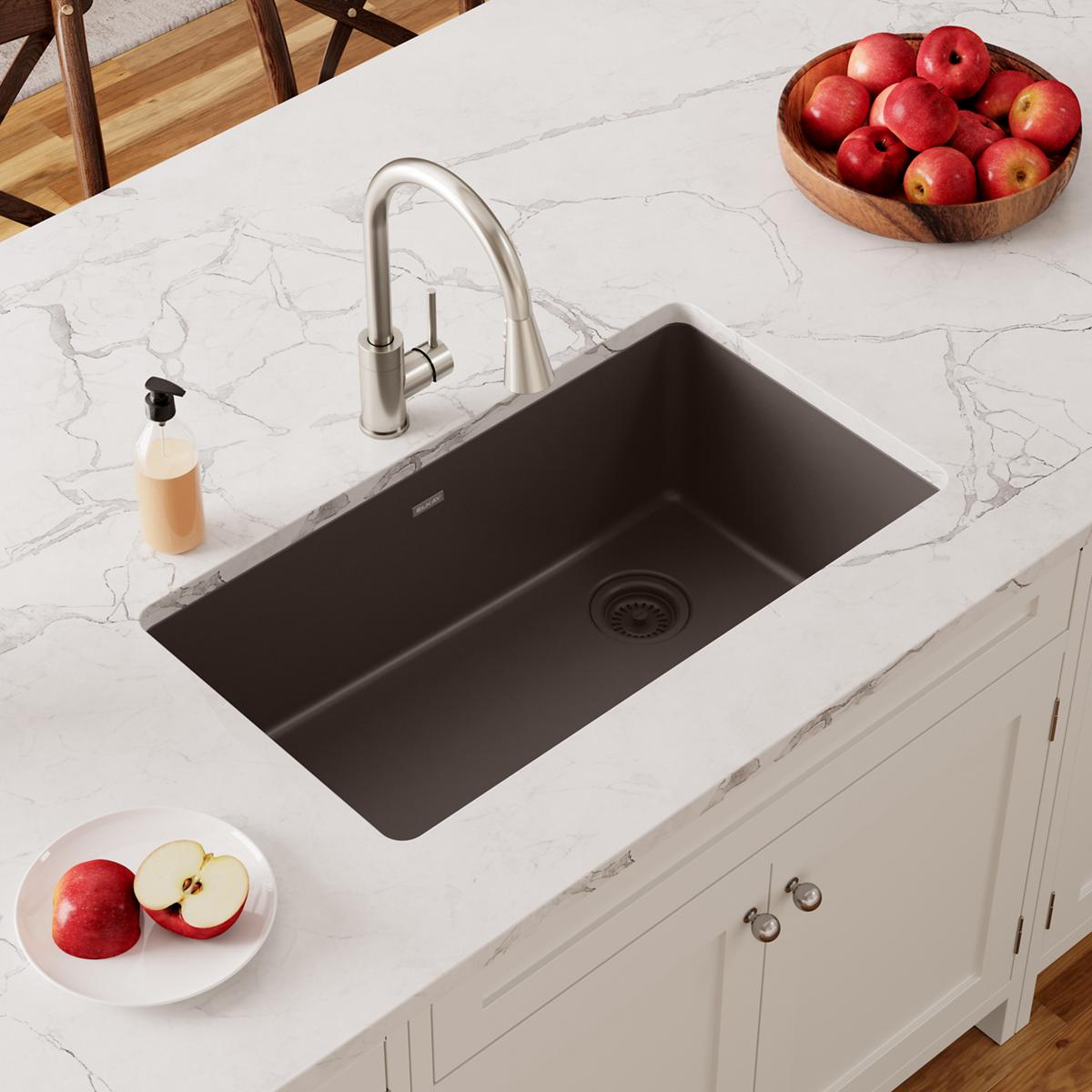 Mocha quartz undermount sink with single rectangular bowl installed in white marble countertop with chrome faucet.