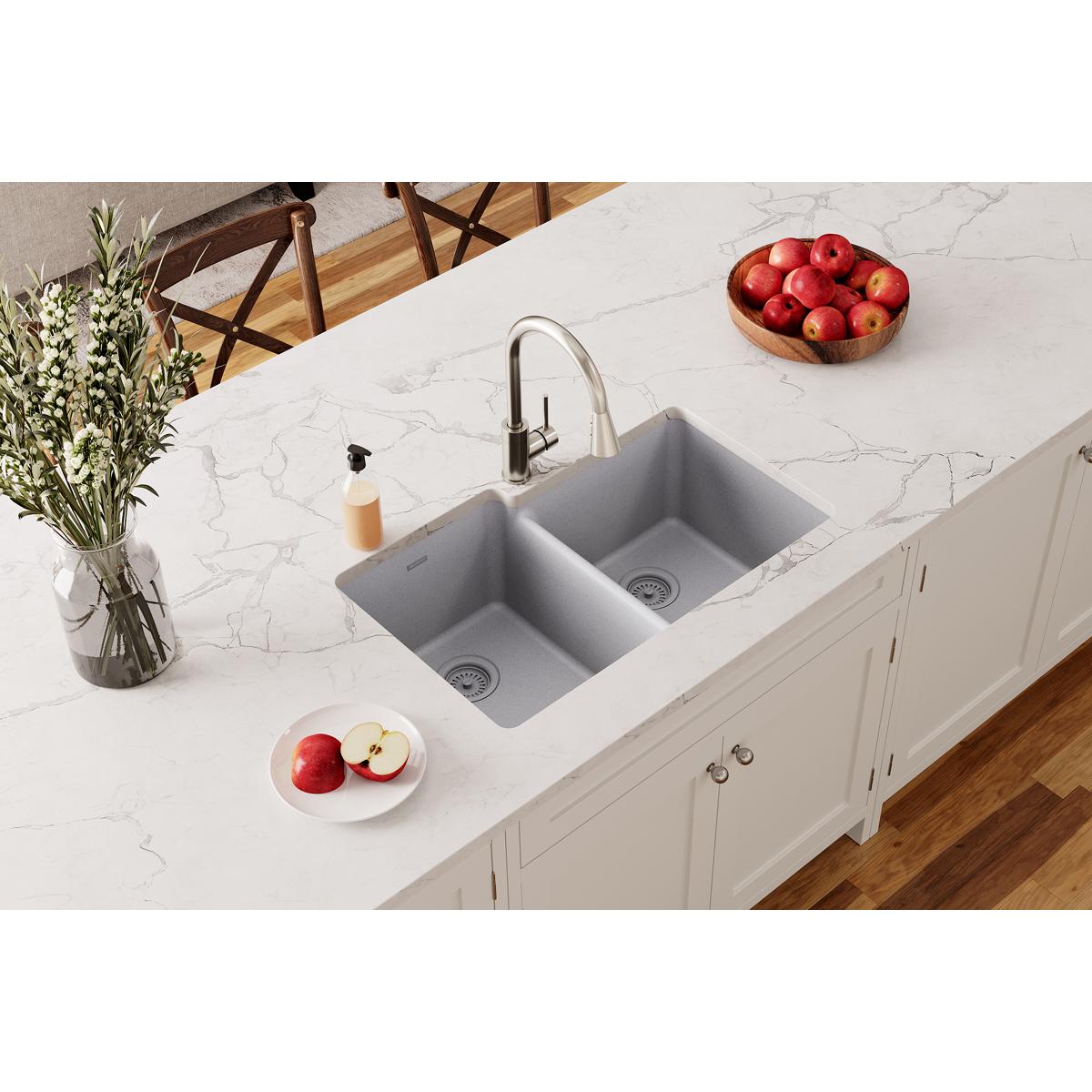 Greystone quartz double bowl undermount sink installed in white marble countertop with faucet.