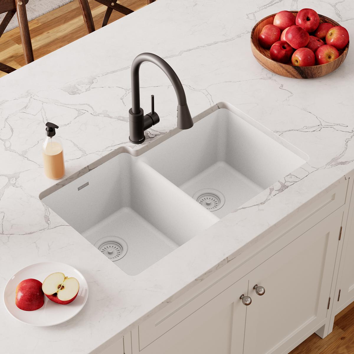 White quartz double bowl undermount sink installed in marble countertop with black faucet and drain strainers visible.
