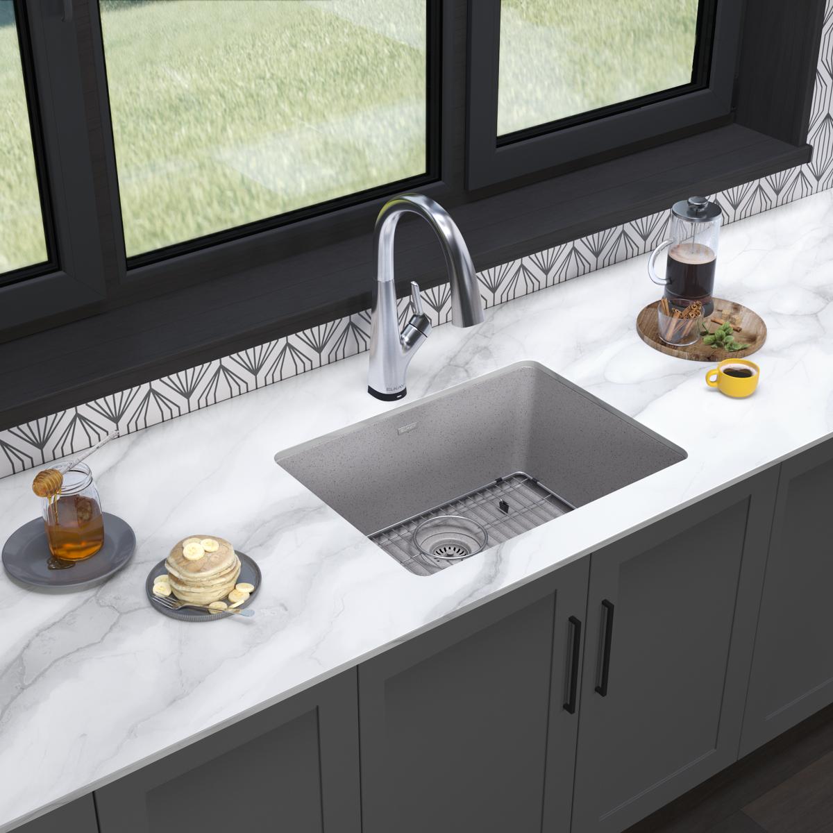 Greystone quartz undermount kitchen sink with single bowl, drain grid, and chrome filtered faucet installed in marble counter