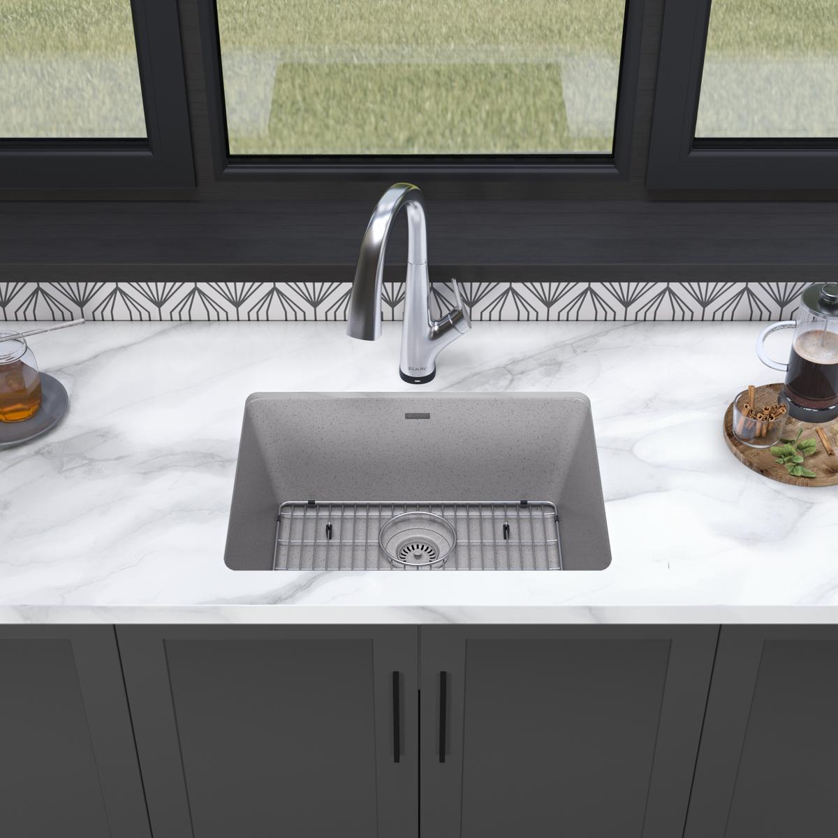 Greystone quartz undermount sink with single bowl, grid strainer, and chrome filtered faucet installed in marble countertop.