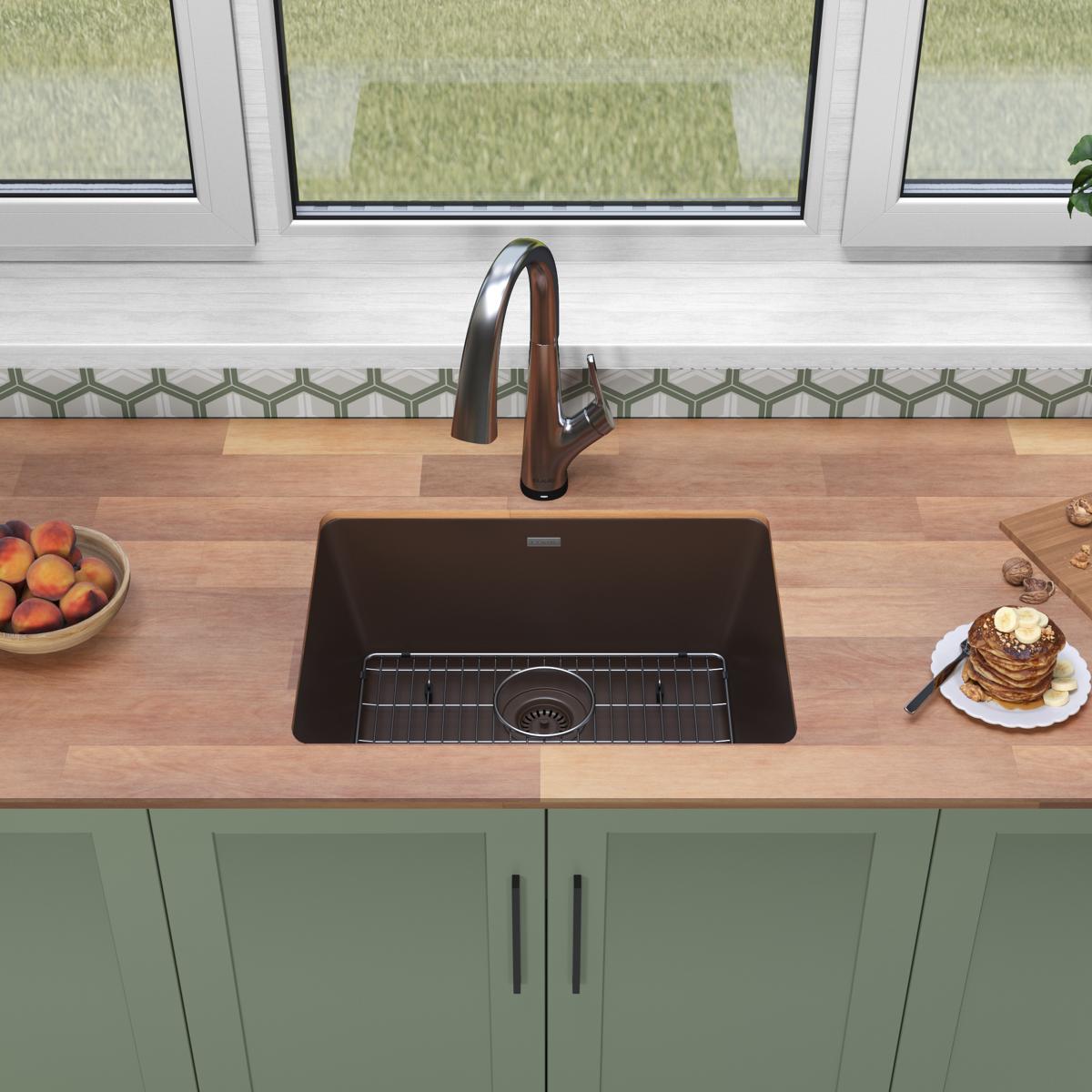 Mocha quartz single bowl undermount sink with filtered faucet installed in wood countertop above green cabinetry.