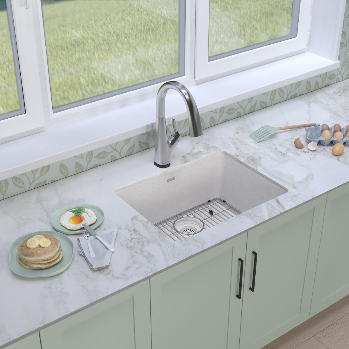 White quartz undermount sink with single bowl and chrome filtered faucet installed in marble countertop.