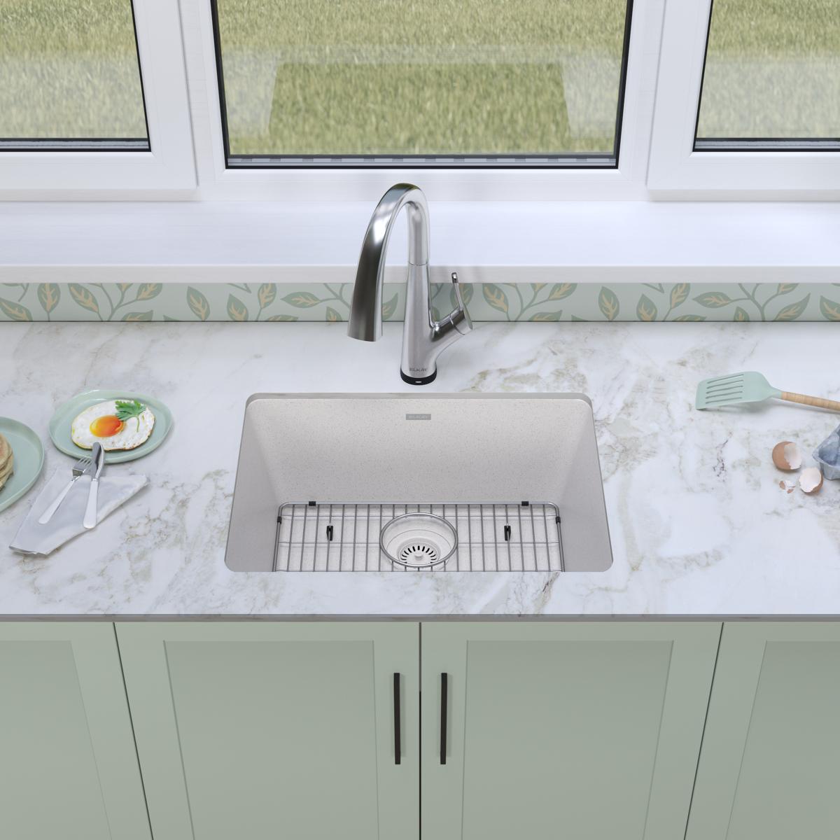 White quartz undermount kitchen sink with single bowl, grid, and stainless steel filtered faucet installed in marble countert