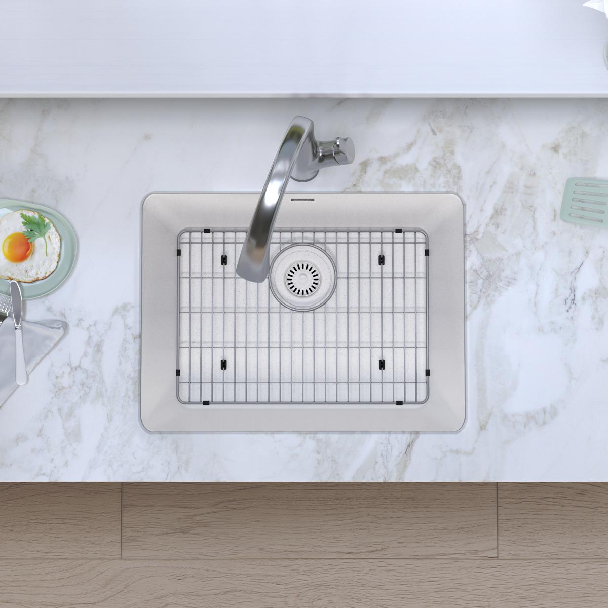 White quartz single bowl undermount sink with stainless steel faucet and grid strainer, installed in marble countertop.