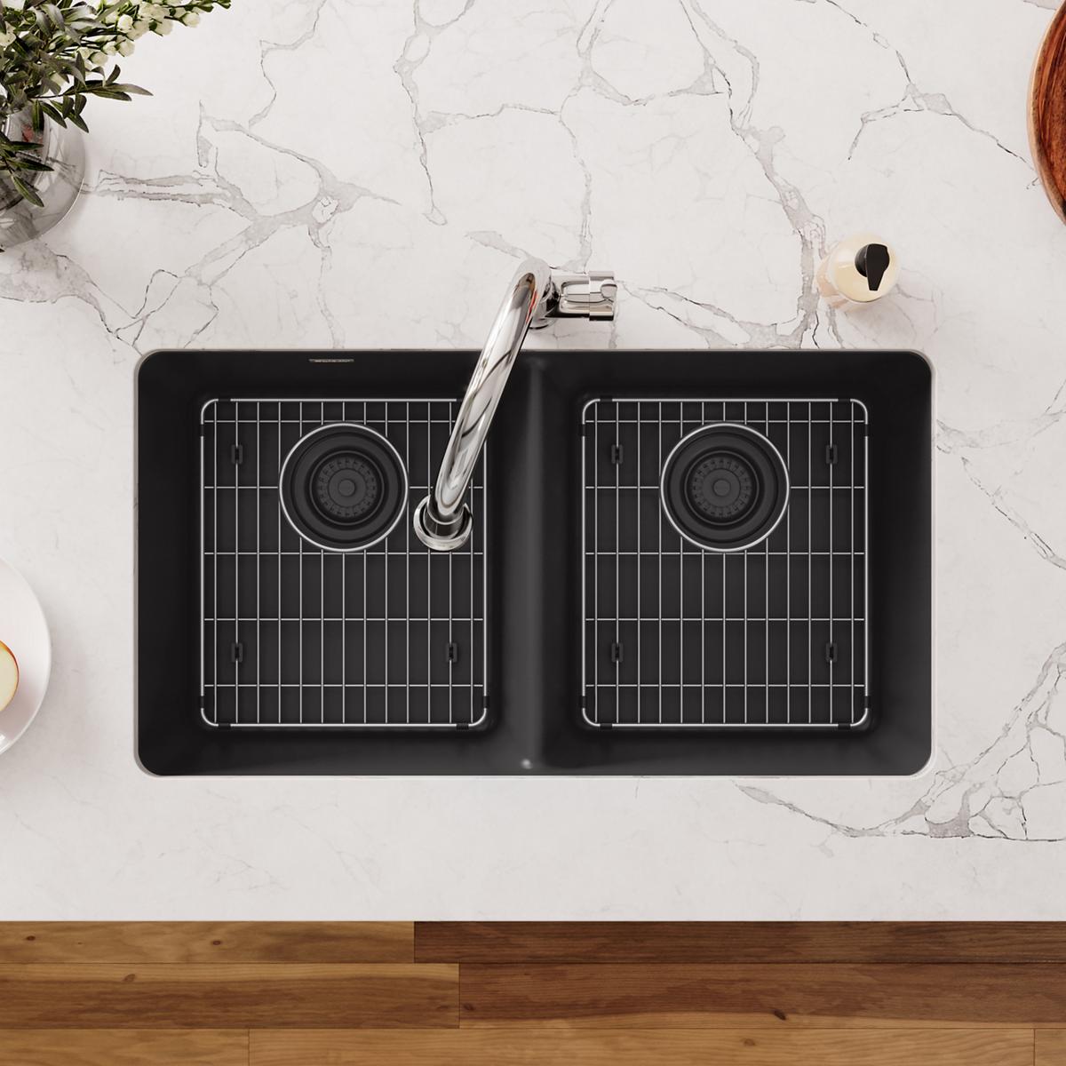 Stainless steel bottom grid with rectangular mesh pattern and circular drain hole placed in black kitchen sink basin.