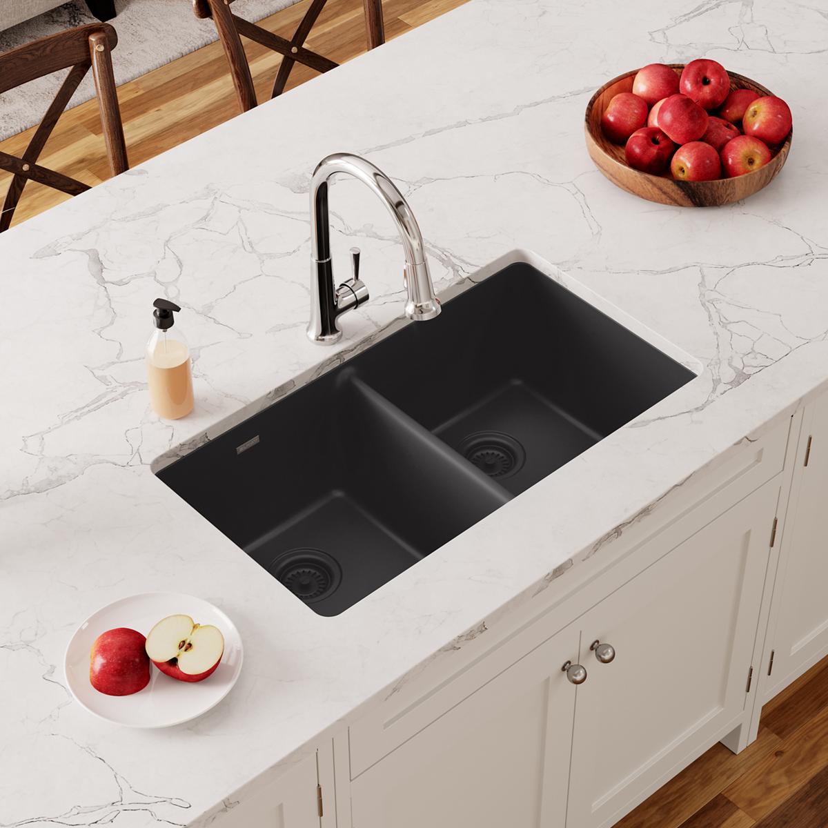 Black quartz undermount double bowl kitchen sink installed in white marble countertop with chrome faucet.