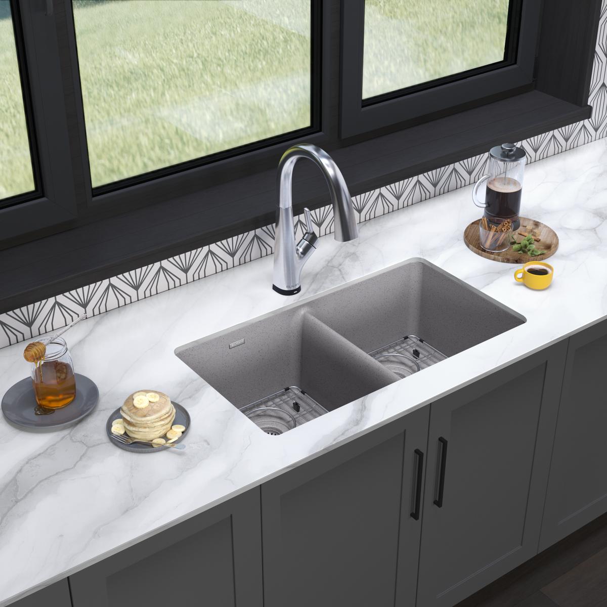 Greystone quartz double bowl undermount sink with chrome filtered faucet installed in white marble countertop.