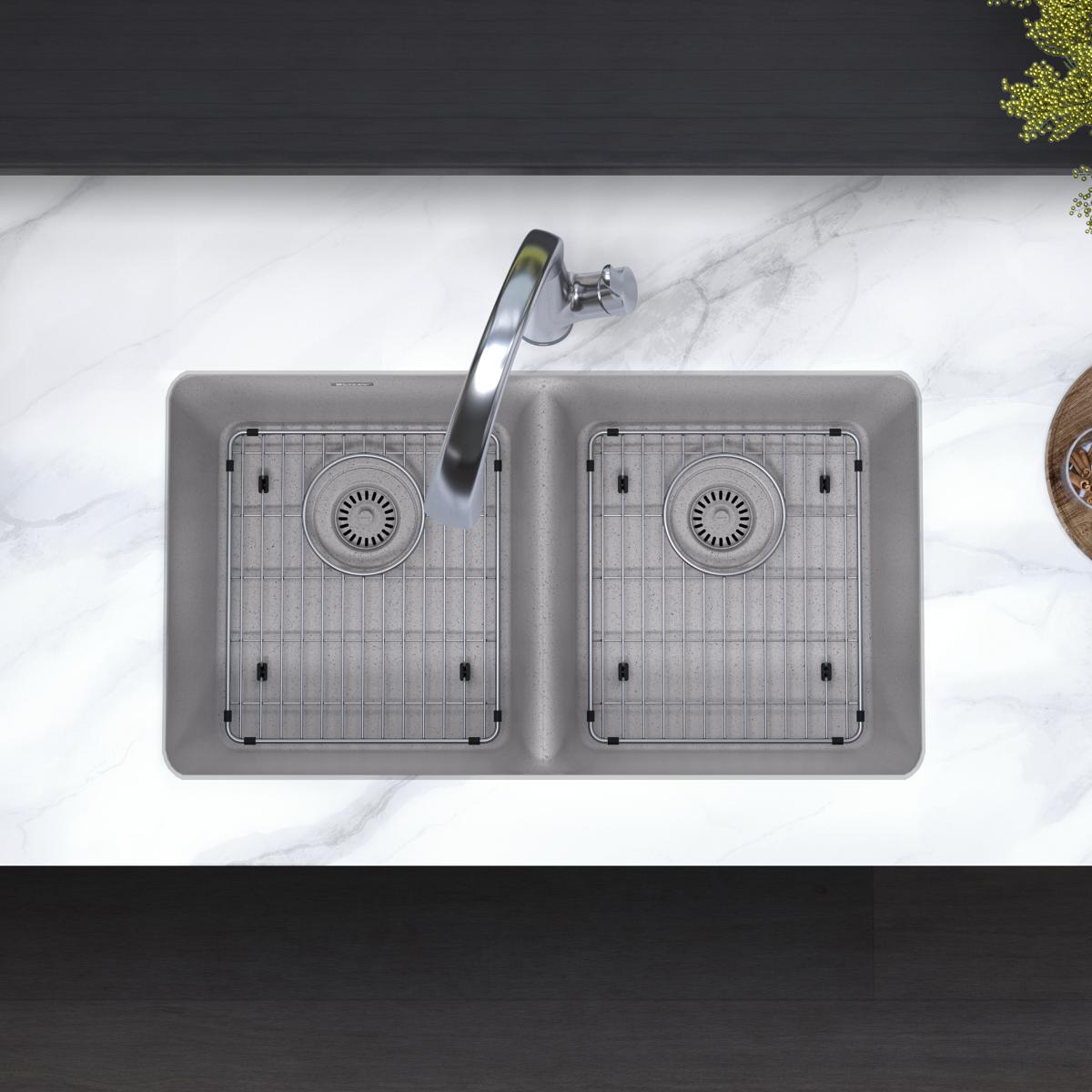 Greystone quartz double bowl undermount sink with dual drains, grid inserts, and curved filtered faucet installed in marble c