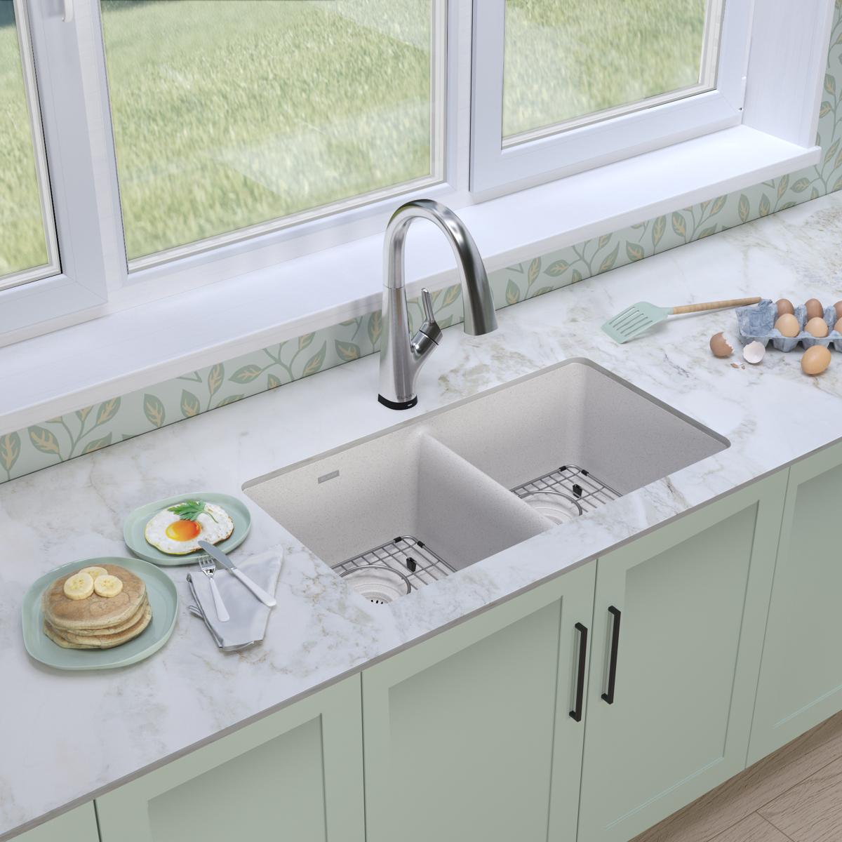 White quartz double bowl undermount sink with chrome pull-down faucet installed in marble countertop with sage green cabinetr