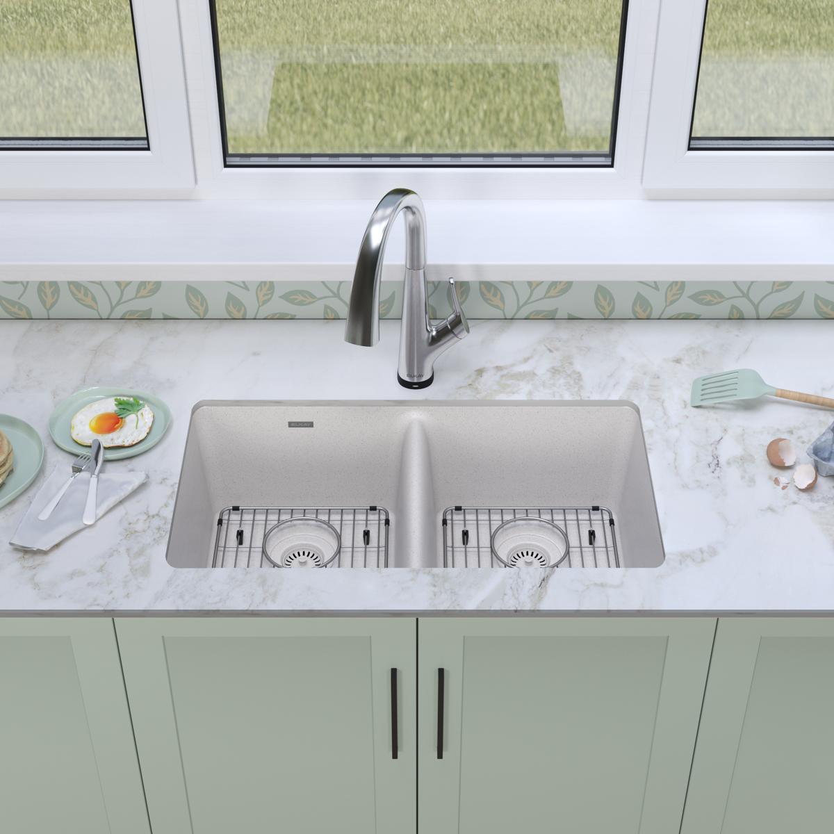 White quartz double bowl undermount sink with stainless steel filtered faucet installed in marble countertop with green cabin