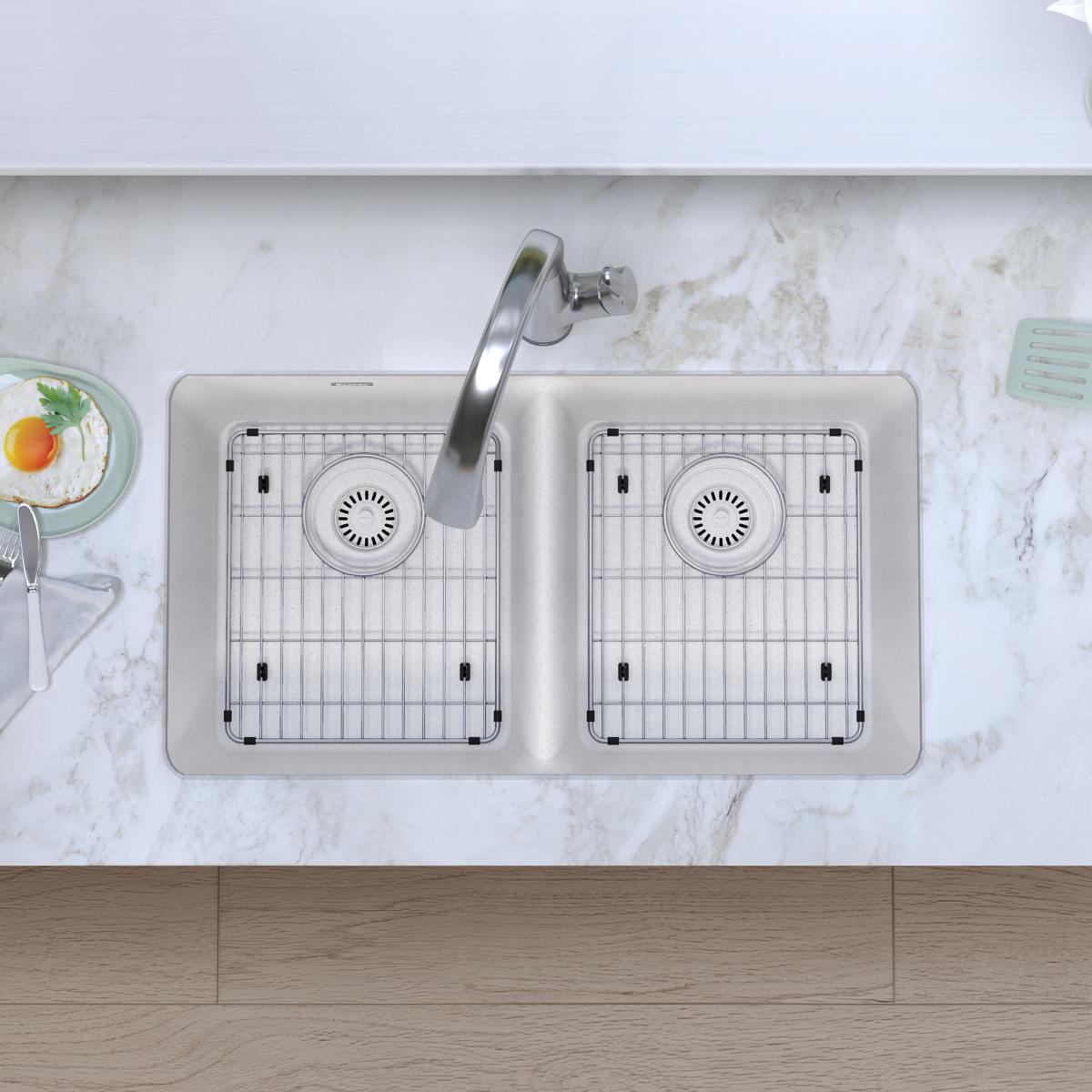 White quartz double bowl undermount sink with two stainless steel grids and a curved filtered faucet installed in marble coun