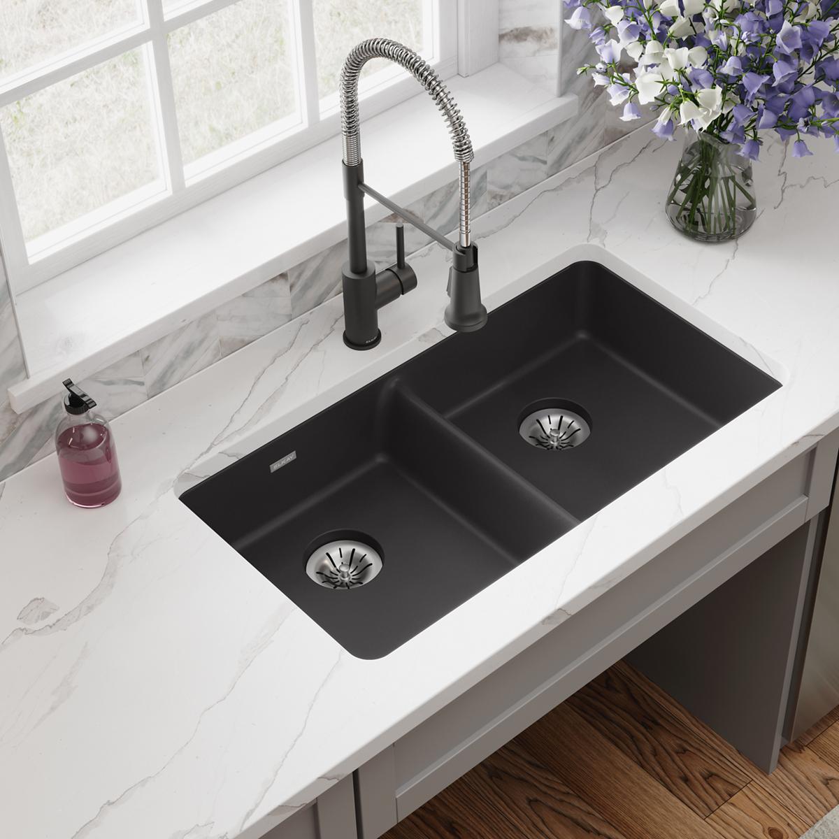 Black quartz double bowl undermount sink with two drain strainers and black pull-down faucet installed in white marble counte