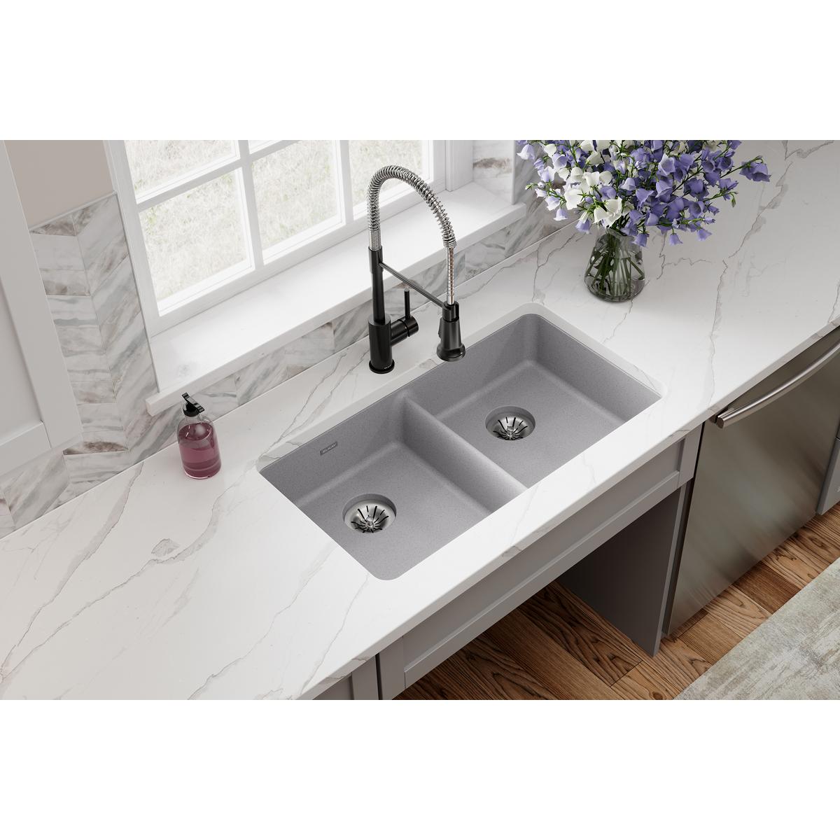 Greystone quartz double bowl undermount sink installed in white marble countertop with black pull-down faucet.