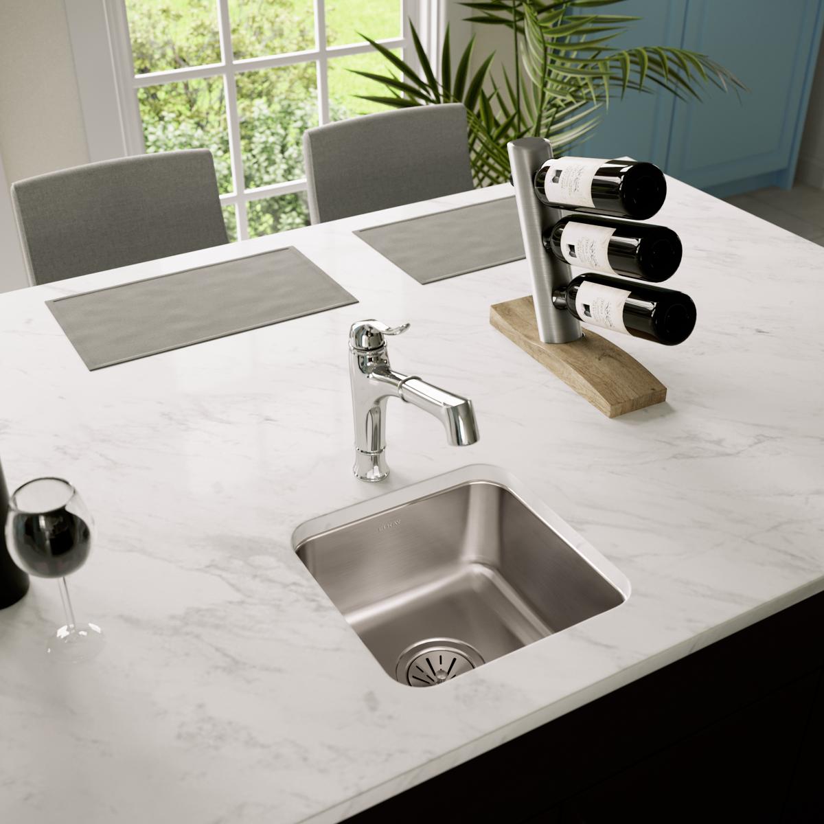 Stainless steel undermount sink installed in white marble countertop with chrome faucet.