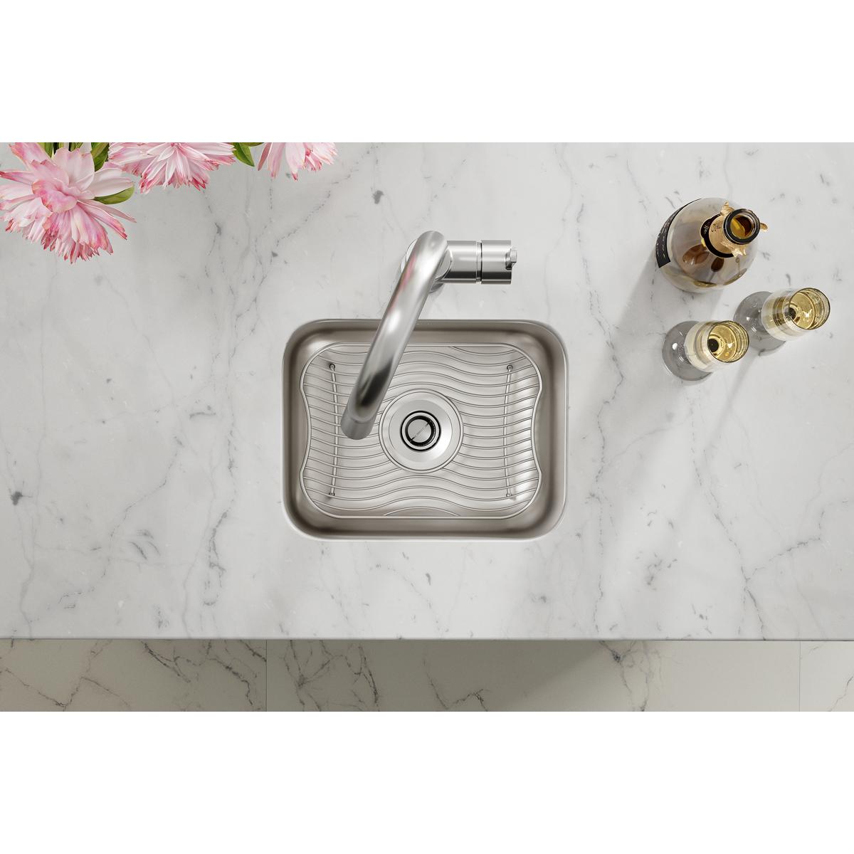 Stainless steel undermount bar sink with wave pattern interior, angled faucet, and sink grid on marble countertop.