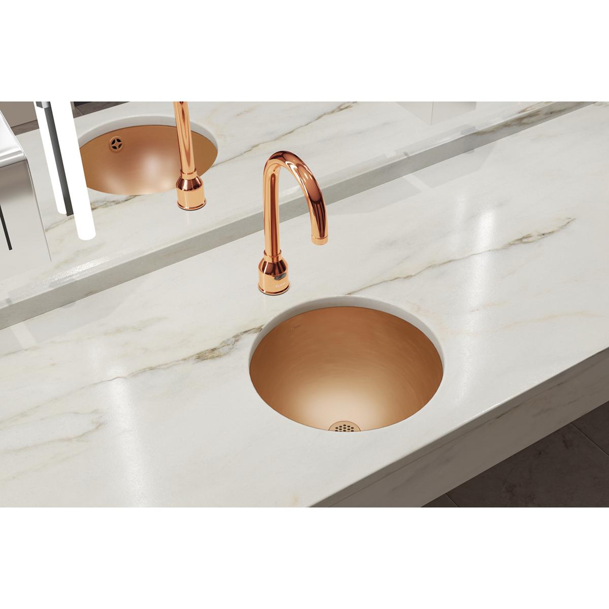 Copper single bowl undermount bathroom sink with matching curved faucet installed in marble countertop.