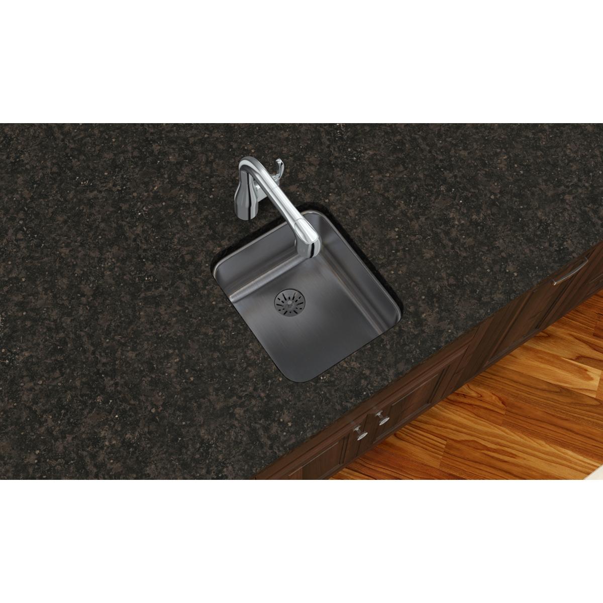 Stainless steel single bowl undermount sink installed in dark granite countertop with wooden cabinet base.