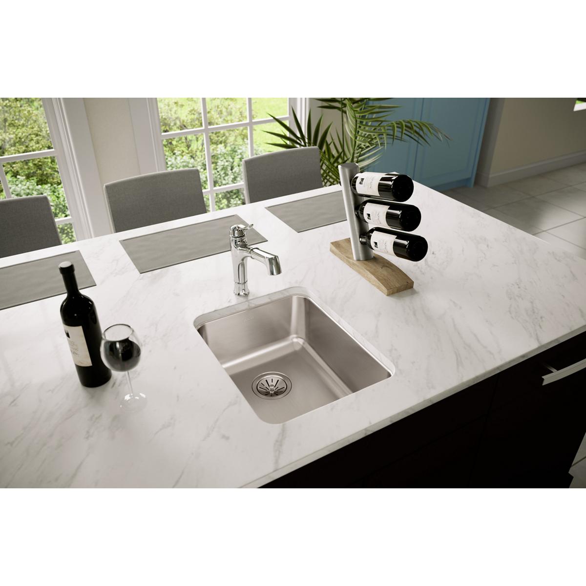 Stainless steel single bowl undermount sink installed in white marble countertop with chrome faucet.