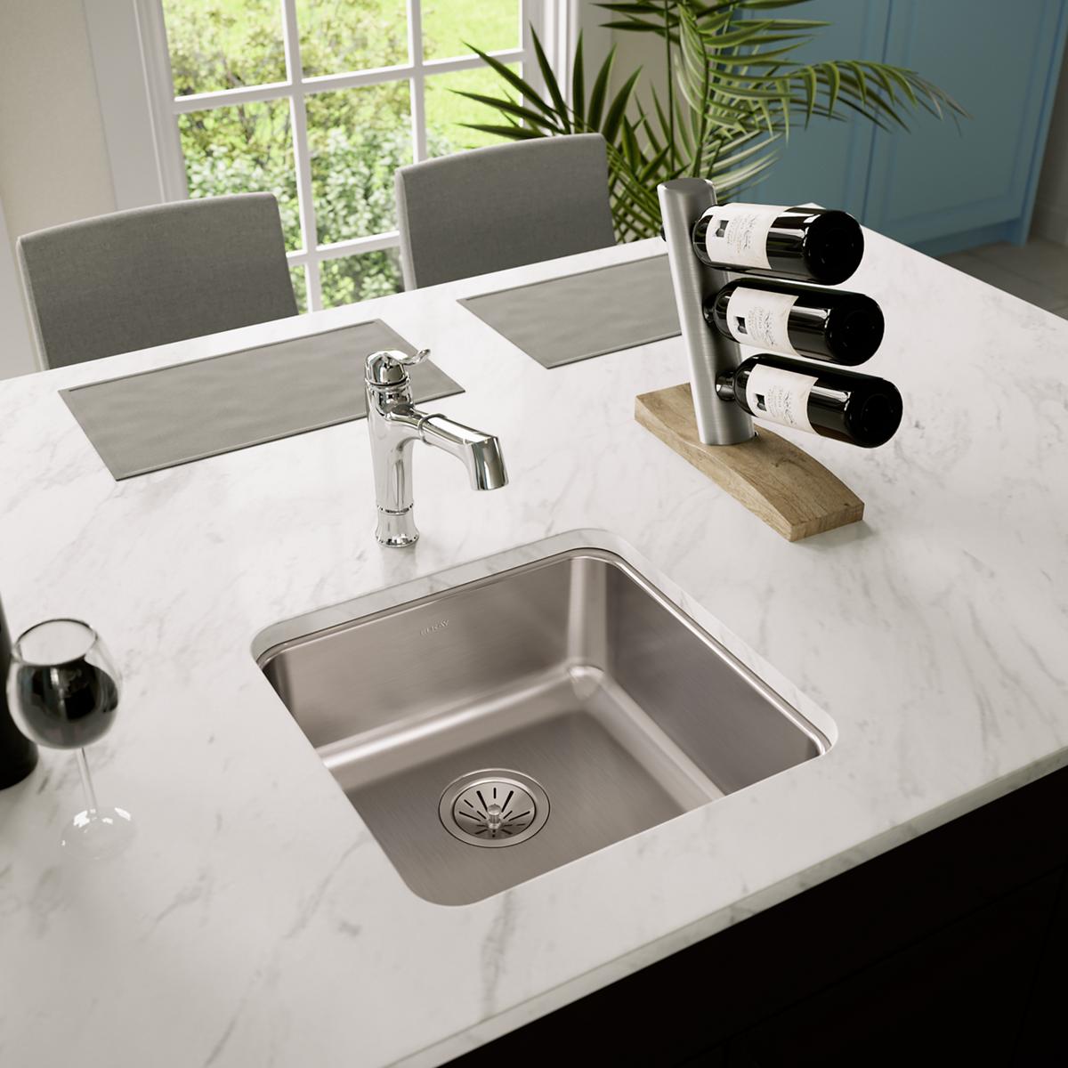 Stainless steel undermount sink installed in white marble countertop with chrome faucet.