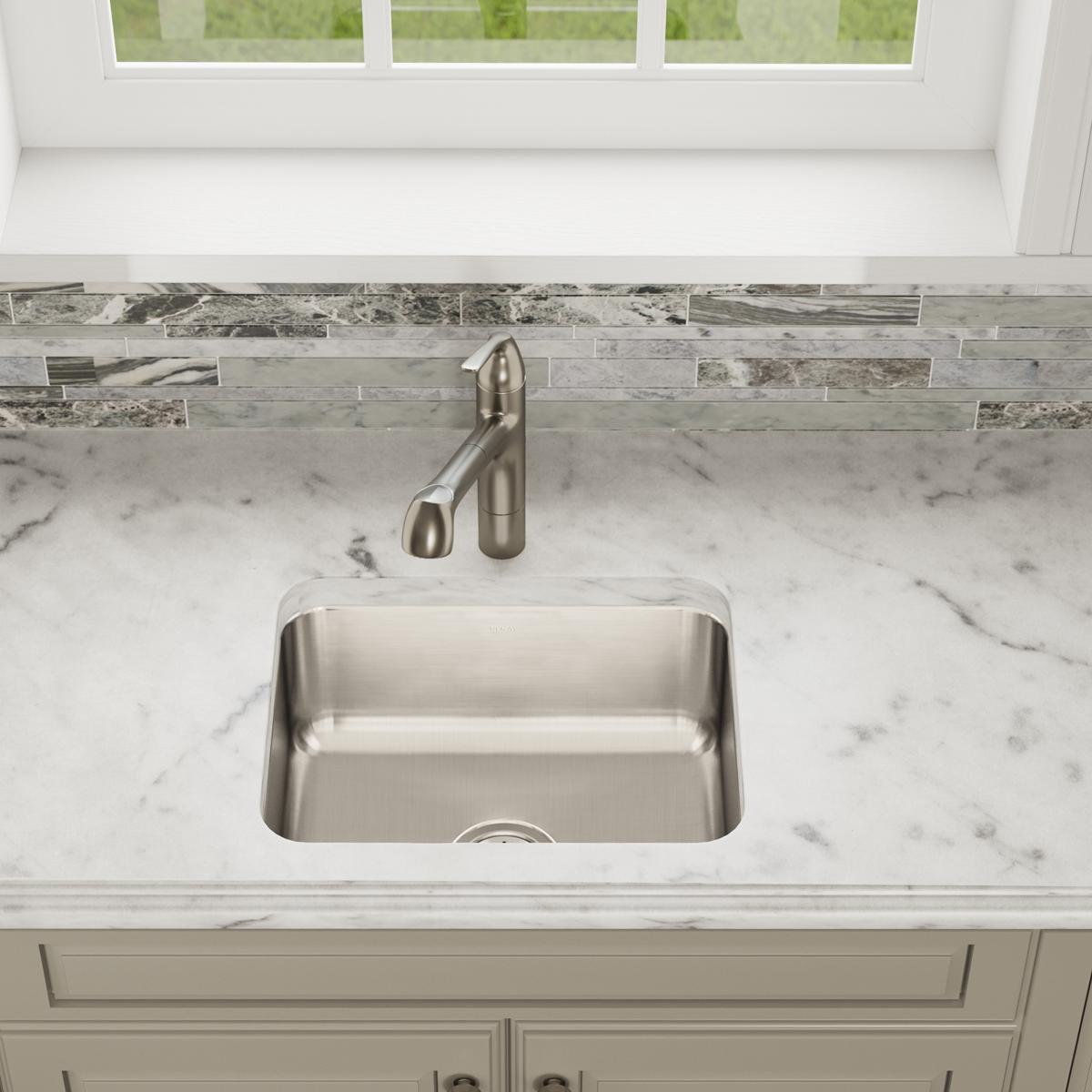 Stainless steel single bowl undermount sink installed in marble countertop with brushed nickel faucet.