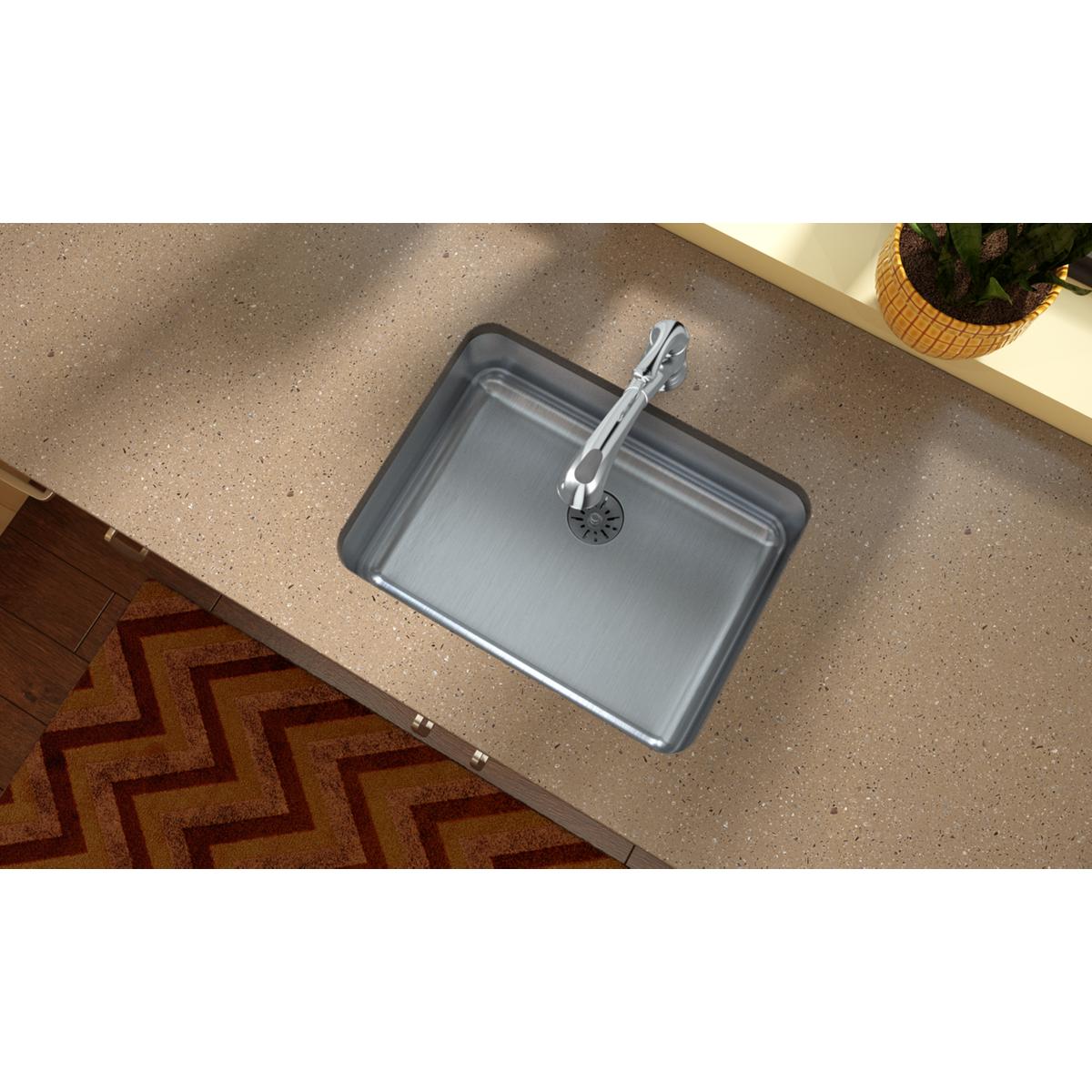 Stainless steel single bowl undermount sink with chrome faucet installed in quartz countertop.