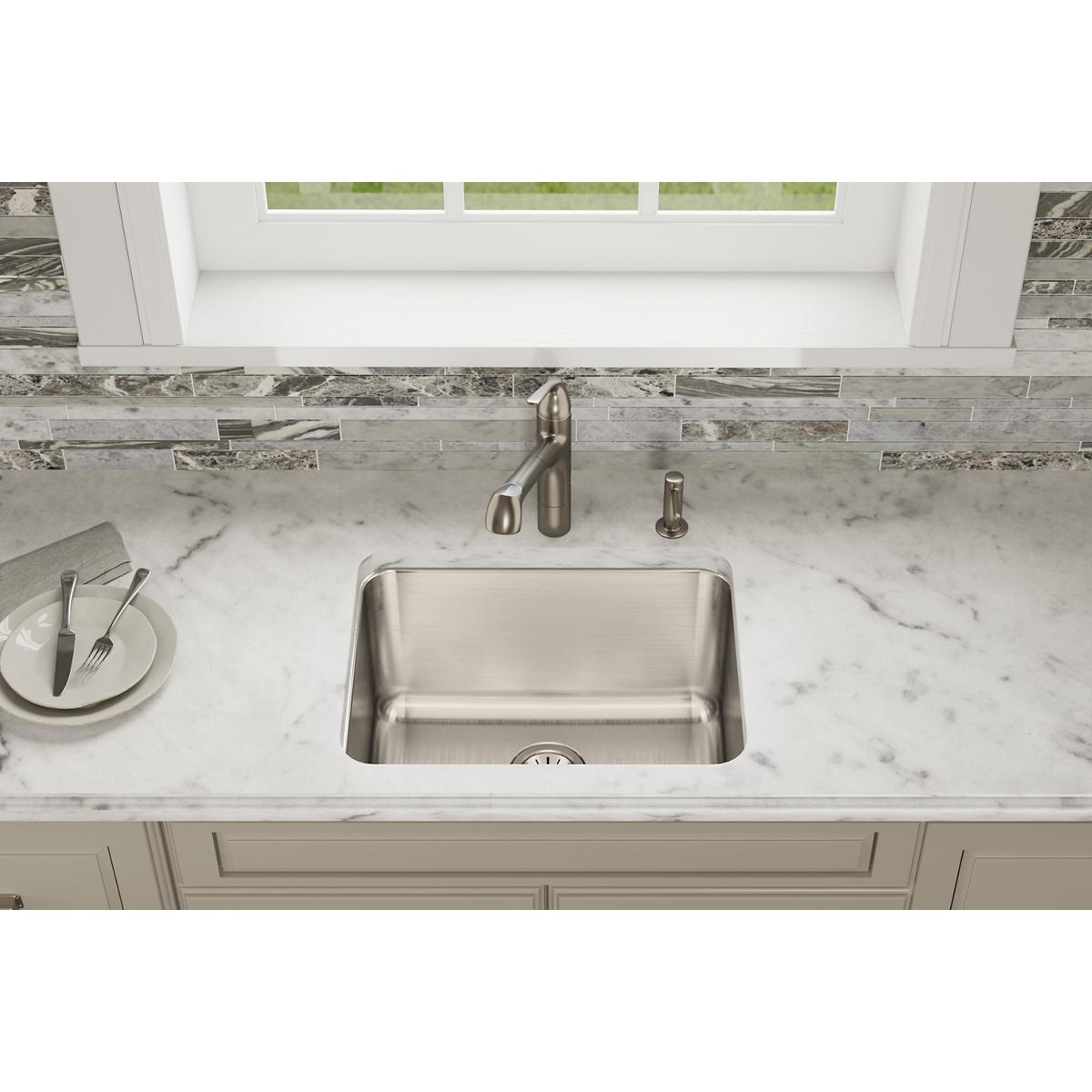 Stainless steel single bowl undermount sink installed in marble countertop with faucet and spray head.