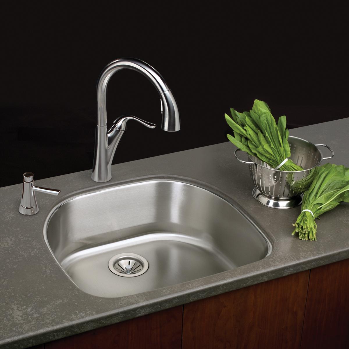 Stainless steel single bowl undermount sink with curved chrome faucet and strainer basket installed in gray countertop.
