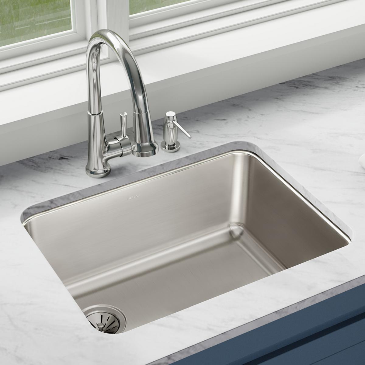 Stainless steel single bowl undermount sink with chrome faucet and soap dispenser installed in marble countertop.