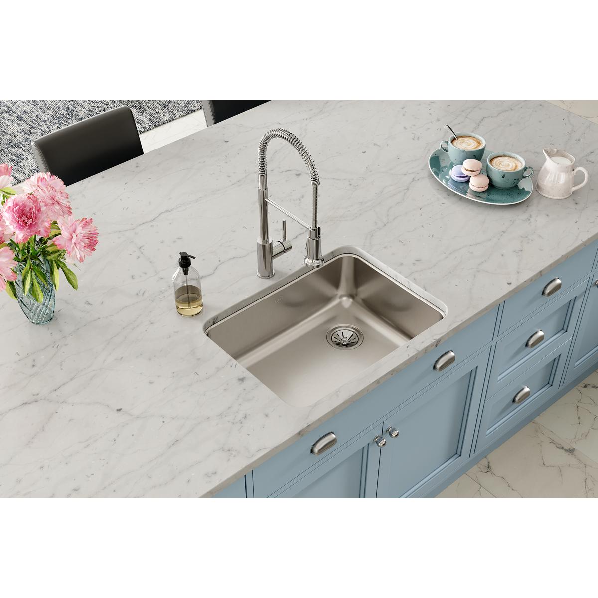 Stainless steel undermount sink with single bowl and right drain installed in marble countertop with faucet.