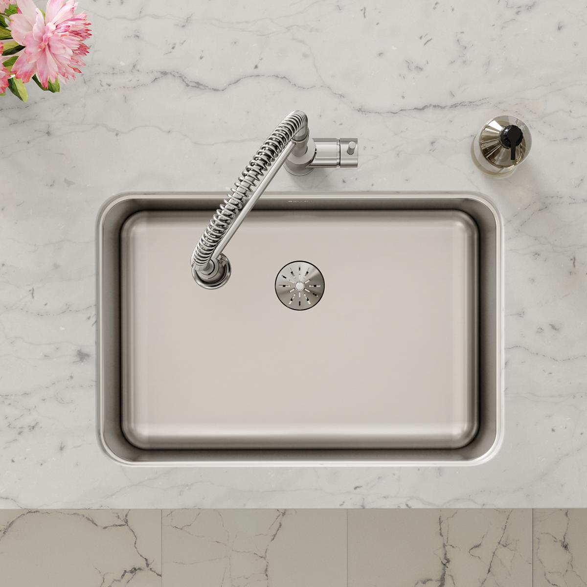 Stainless steel single bowl undermount sink with drain and flexible spray hose on marble countertop.