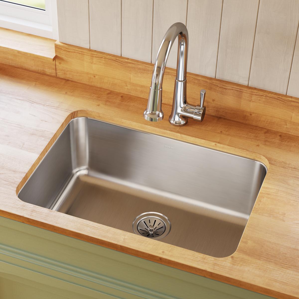 Stainless steel undermount sink with single bowl installed in wooden countertop, chrome faucet visible above.