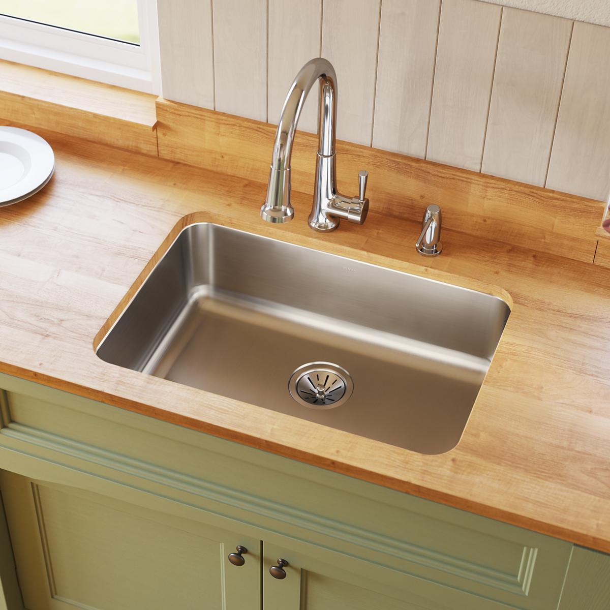 Stainless steel single bowl undermount sink installed in wood countertop with chrome faucet and drain.