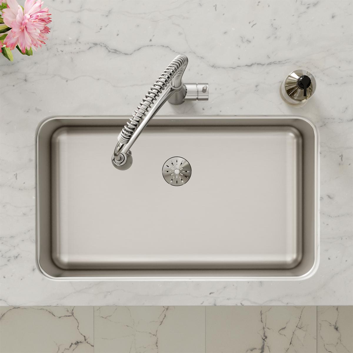 Stainless steel undermount sink with single bowl, drain cover, and curved spray faucet installed in marble countertop.