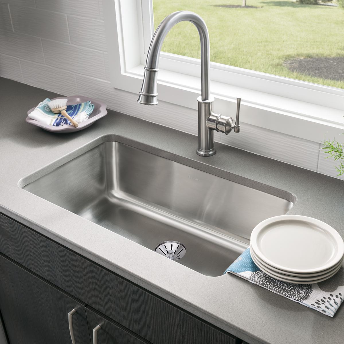 Stainless steel single bowl undermount sink installed in countertop with pull-down faucet and drain visible.