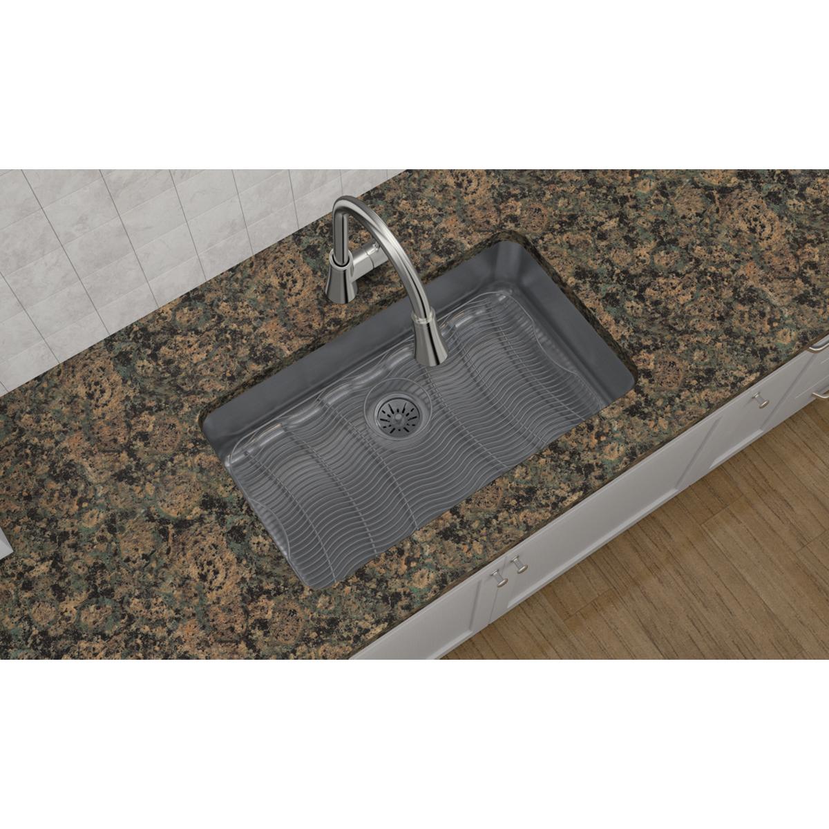 Stainless steel undermount sink with single bowl, ribbed basin, and drain installed in granite countertop.