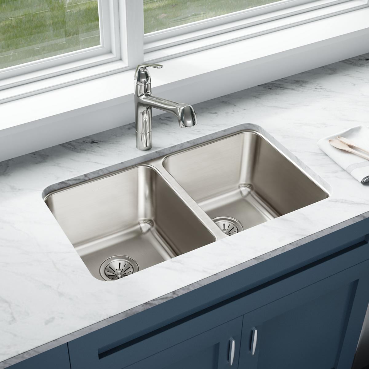 Stainless steel double bowl undermount sink installed in marble countertop with chrome faucet and drain strainers.