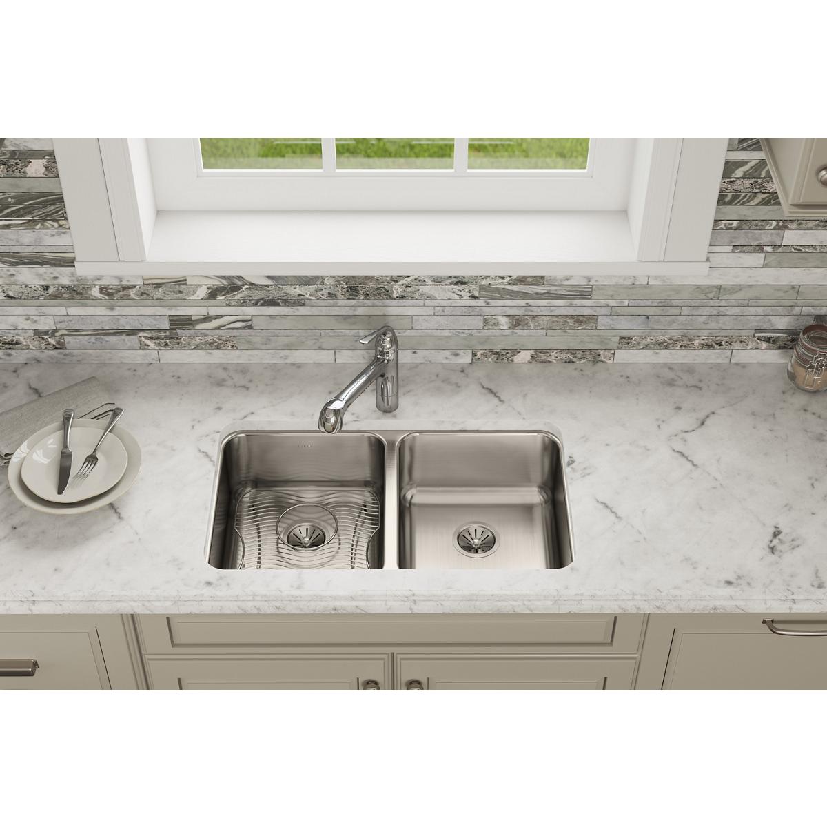 Stainless steel double bowl undermount sink installed in marble countertop with chrome faucet.