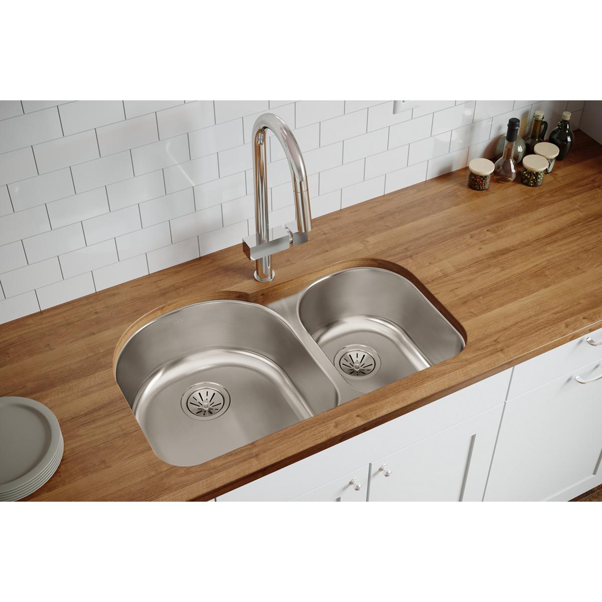 Stainless steel double bowl undermount sink with offset 60/40 configuration installed in wooden countertop with chrome faucet