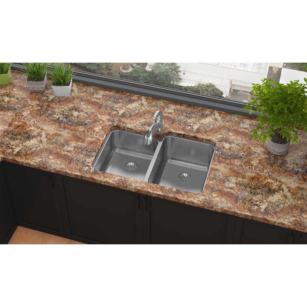 Stainless steel double bowl undermount sink installed in granite countertop with chrome faucet.