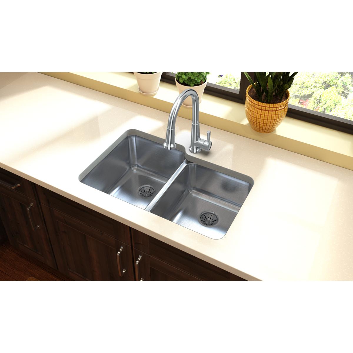 Stainless steel double bowl undermount sink with drain baskets and chrome faucet installed in cream countertop.