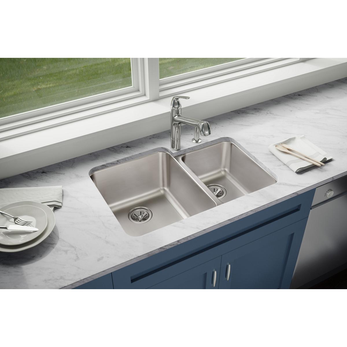 Stainless steel double bowl undermount sink with offset 60/40 configuration installed in white marble countertop.