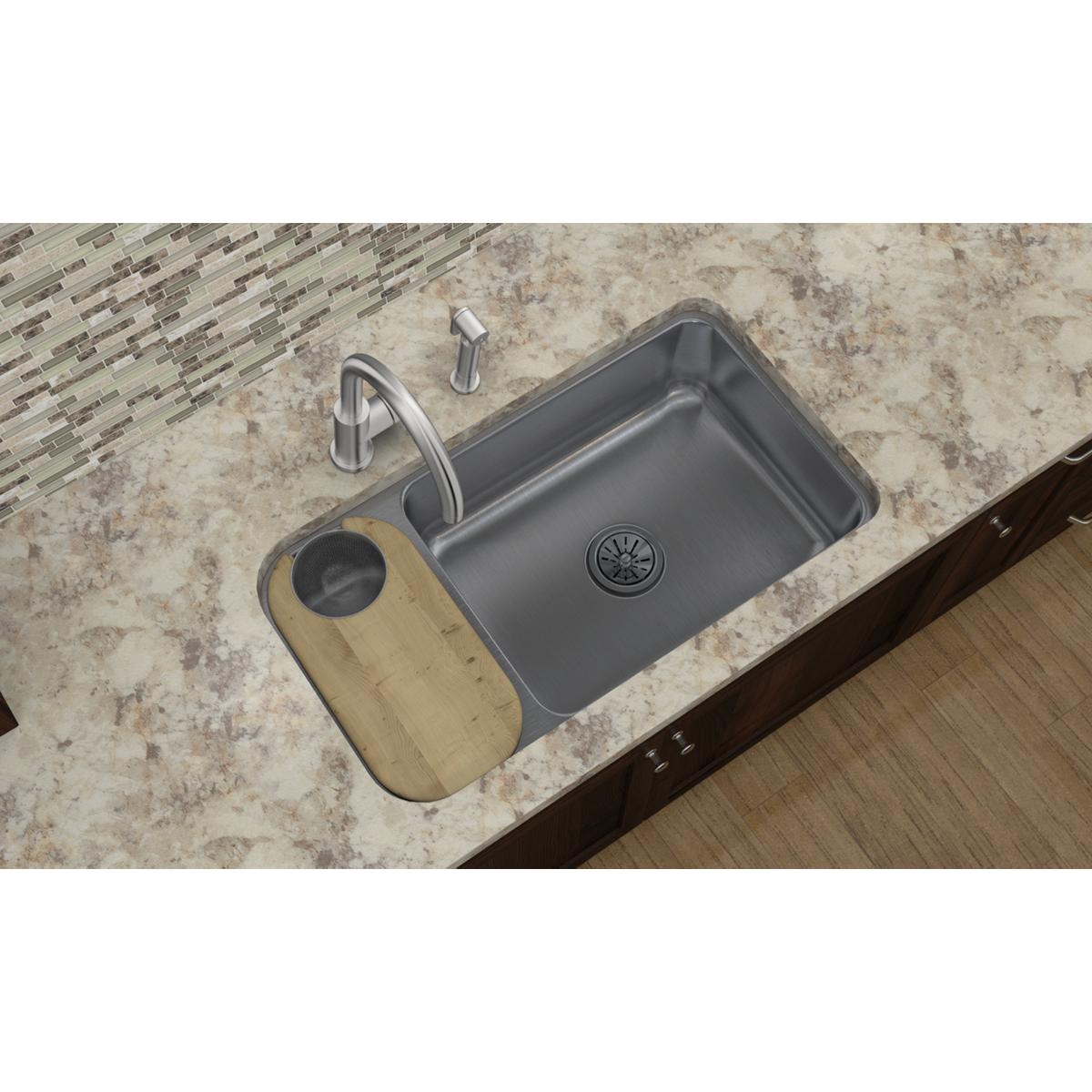 Light wood cutting board positioned next to gray kitchen sink on countertop.