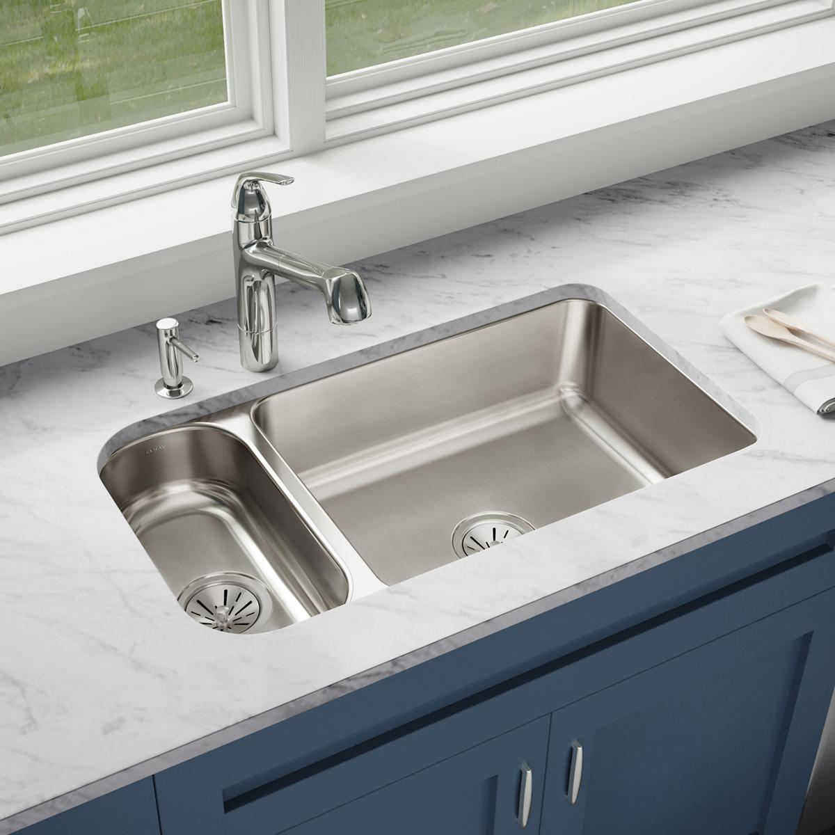 Stainless steel double bowl undermount sink with smaller left bowl and larger right bowl installed in white marble countertop