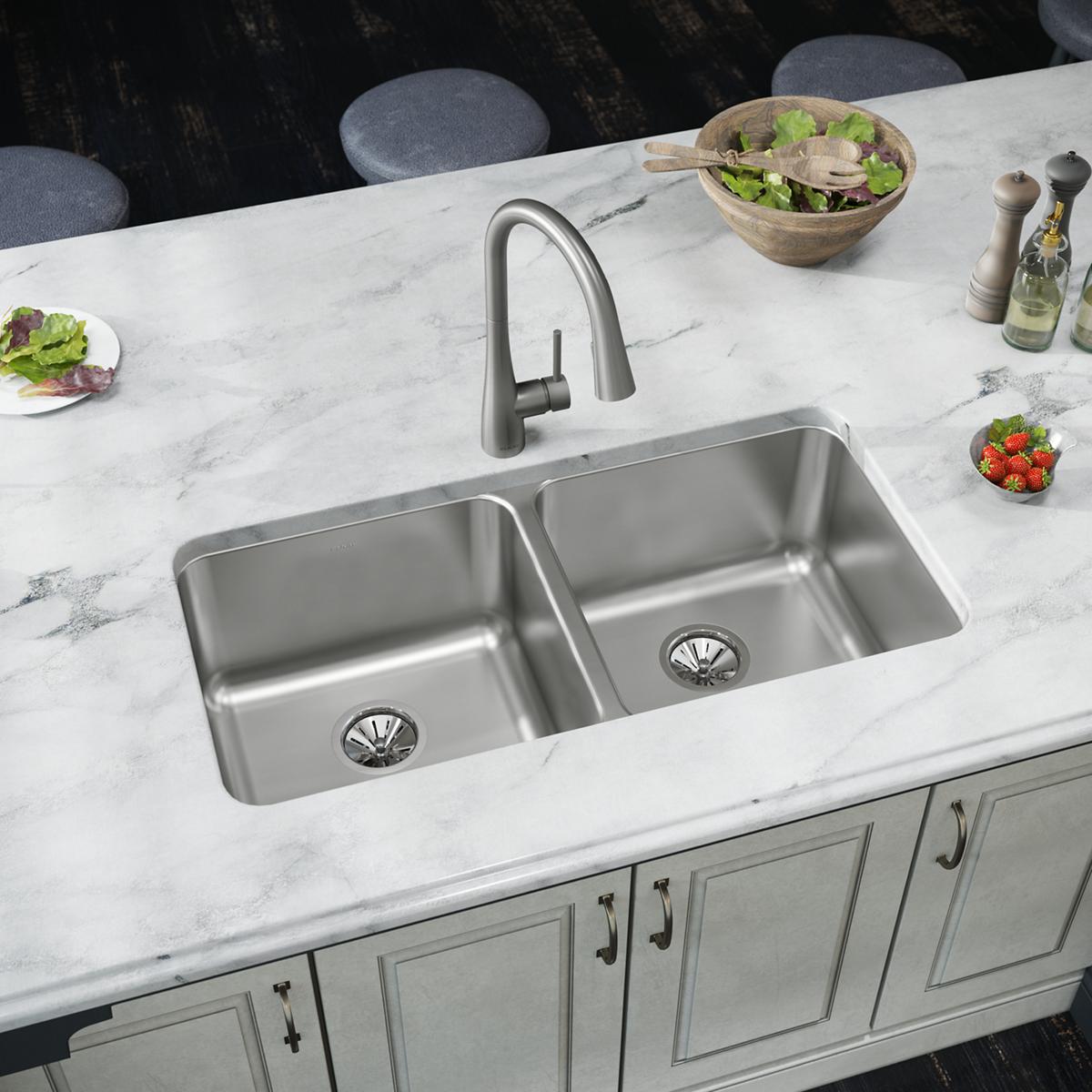 Stainless steel double bowl undermount sink installed in marble countertop with arc faucet.