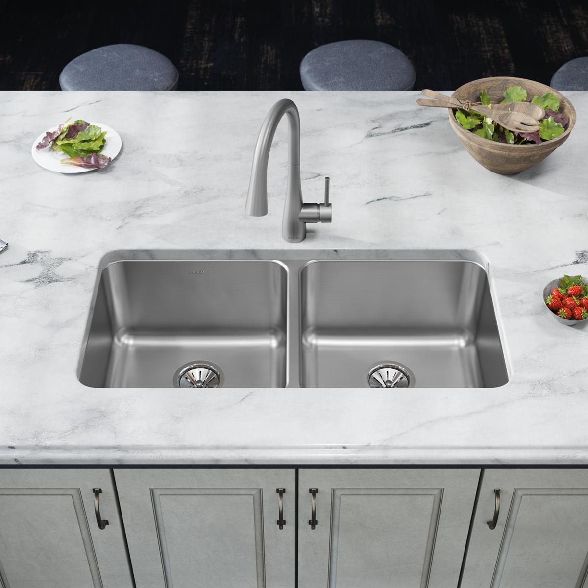 Stainless steel double bowl undermount sink installed in marble countertop with faucet and drain strainers visible.