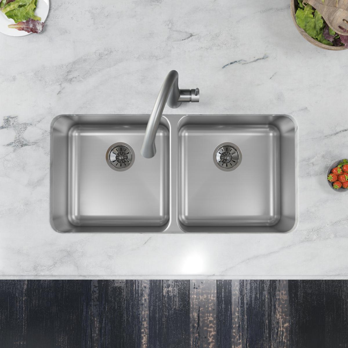 Stainless steel double bowl undermount sink with two equal-sized basins, drain strainers, and curved faucet installed in marb
