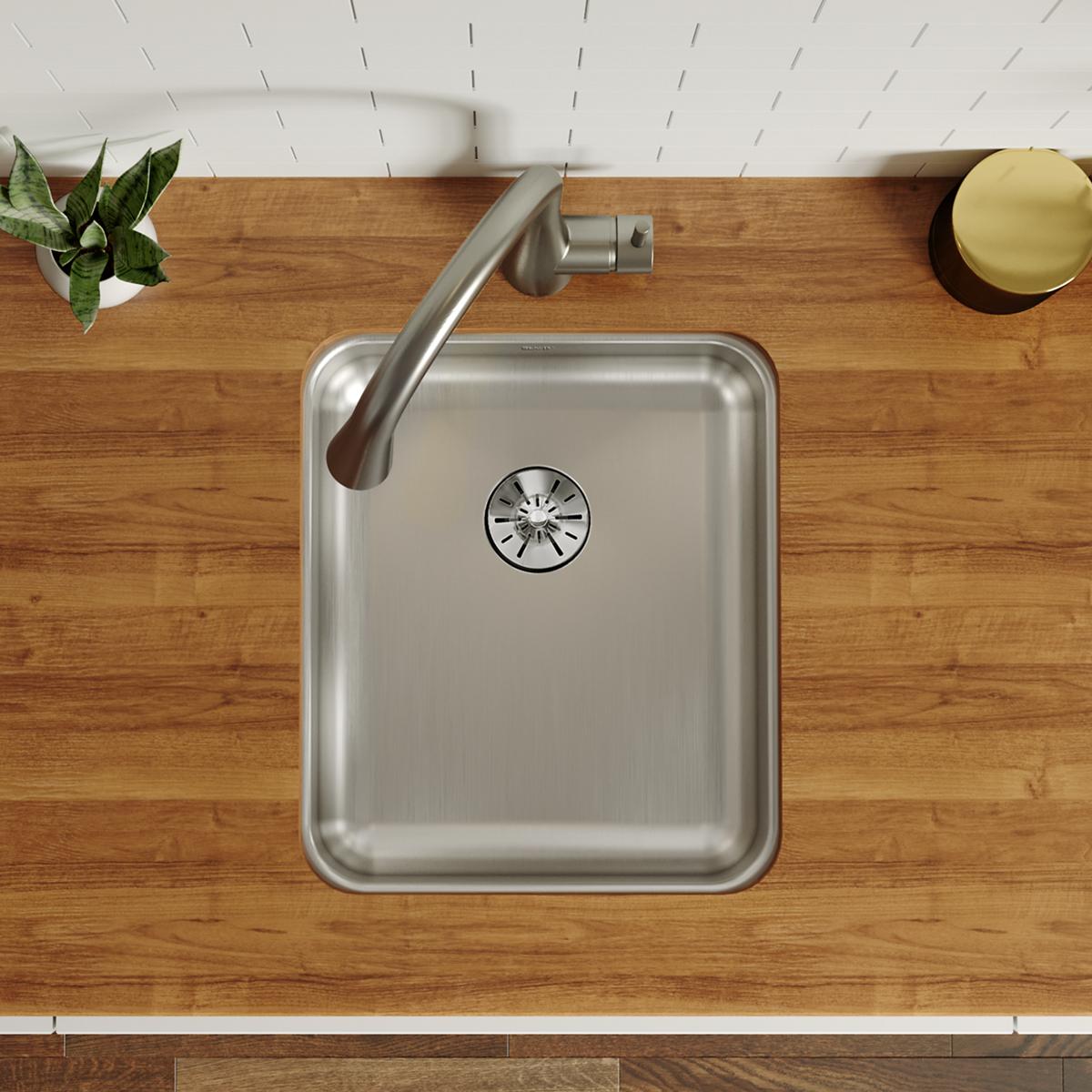 Stainless steel single bowl undermount sink installed in wooden countertop with faucet and drain visible from above.