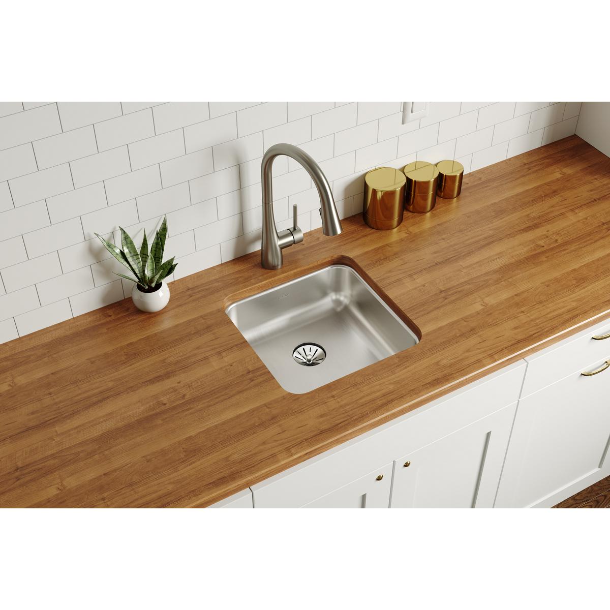 Stainless steel undermount sink with single bowl installed in wooden countertop with faucet and drain visible.