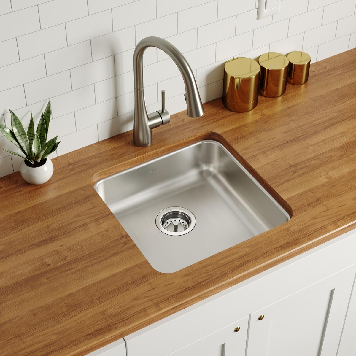 Stainless steel square single bowl sink undermounted in wood countertop with stainless steel faucet and white subway tile bac